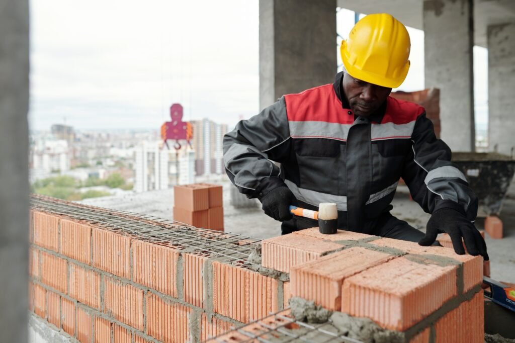 Experienced builder flattening surface of brick layer with special hammer